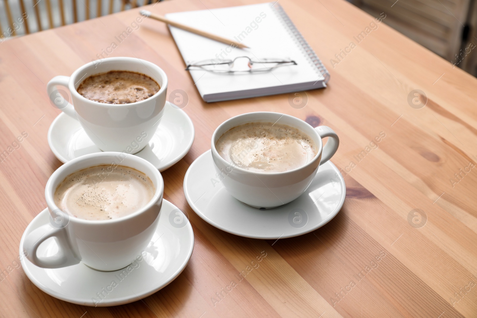 Photo of Cups of aromatic coffee on wooden table