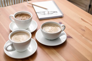 Cups of aromatic coffee on wooden table