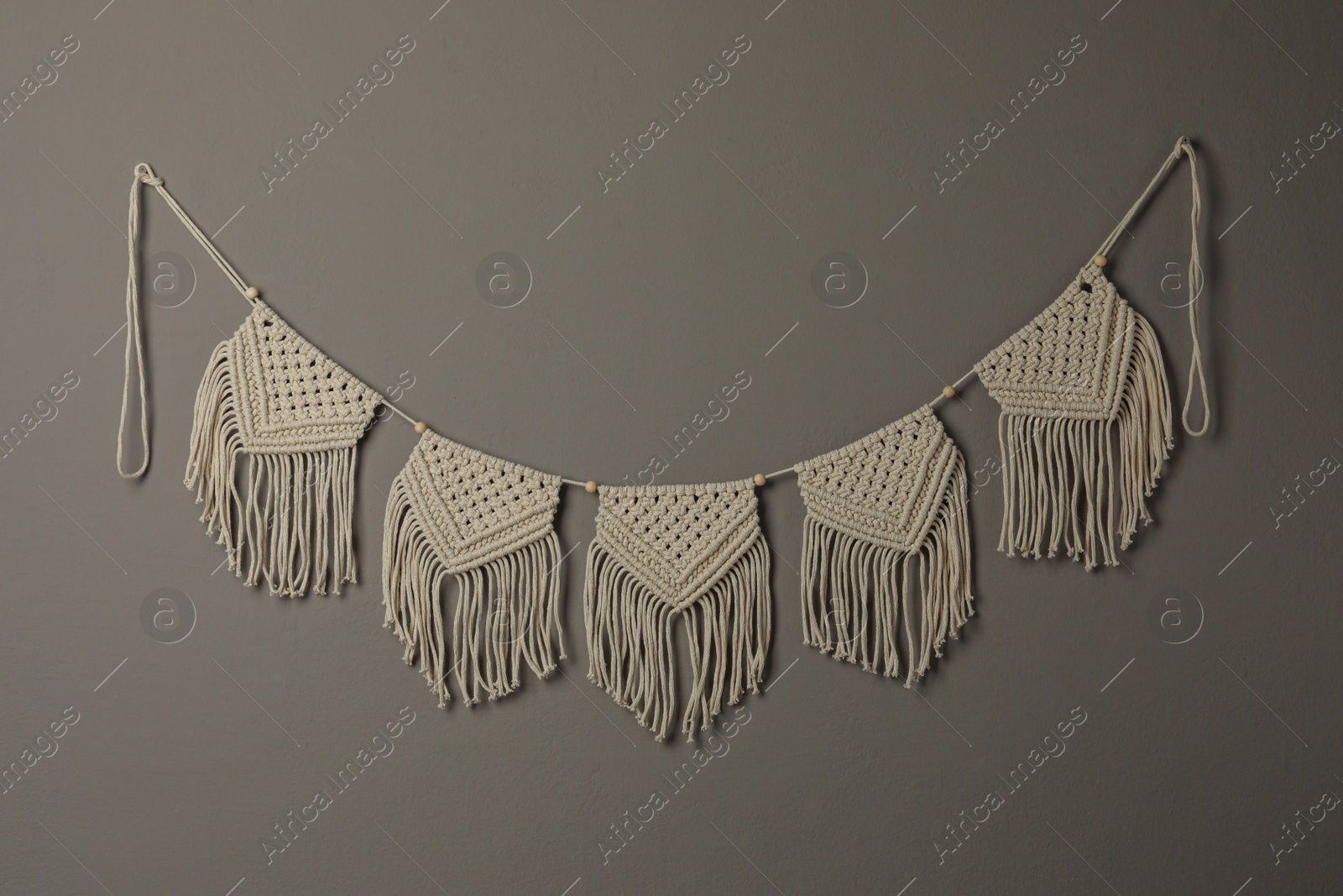 Photo of Beautiful large macrame hanging on grey wall. Decorative element