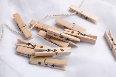 Pile of wooden clothespins and twine on white fabric