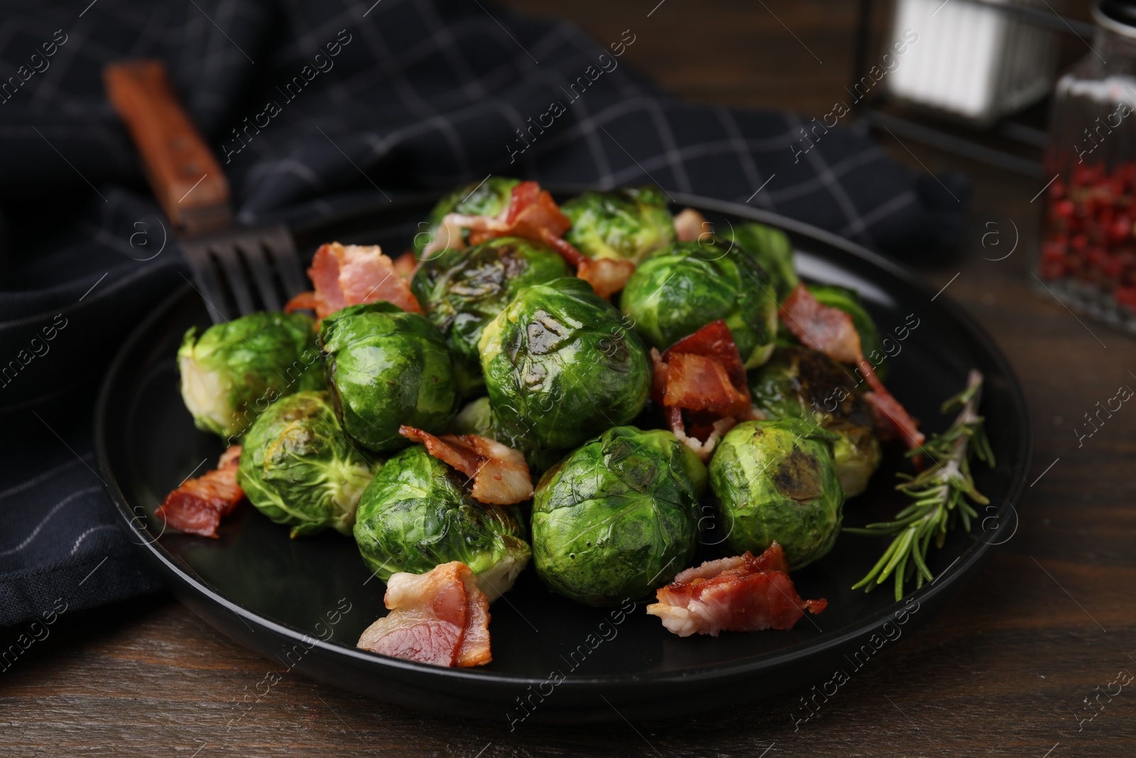 Photo of Delicious roasted Brussels sprouts and bacon on wooden table, closeup