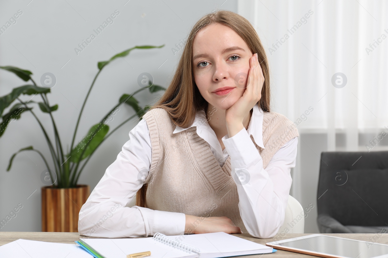 Photo of Portrait of woman at table with notebook, pen and tablet in office