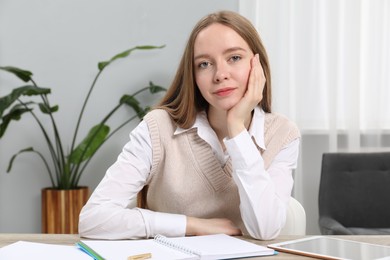 Photo of Portrait of woman at table with notebook, pen and tablet in office