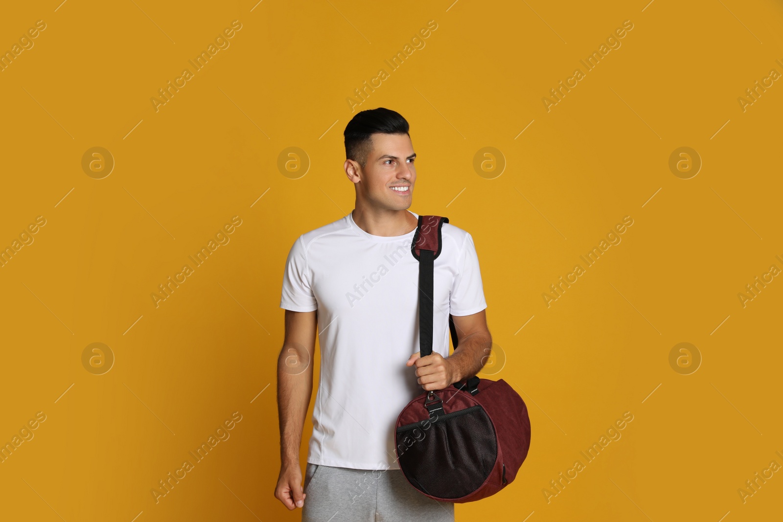 Photo of Handsome man with sports bag on yellow background