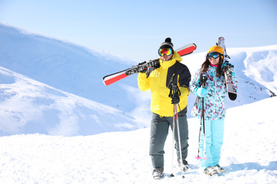 Photo of Young couple with skis on hill, space for text. Winter vacation