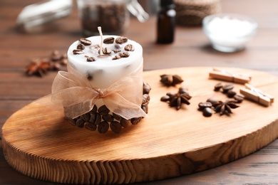 Photo of Board with coffee candle and beans on wooden table. Space for text