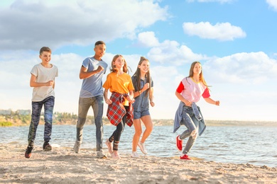 Image of School holidays. Group of happy children running on beach