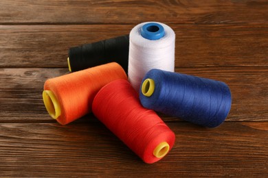 Different colorful sewing threads on wooden background