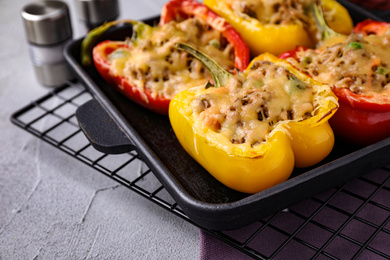 Photo of Tasty stuffed bell peppers in baking pan on grey table, closeup