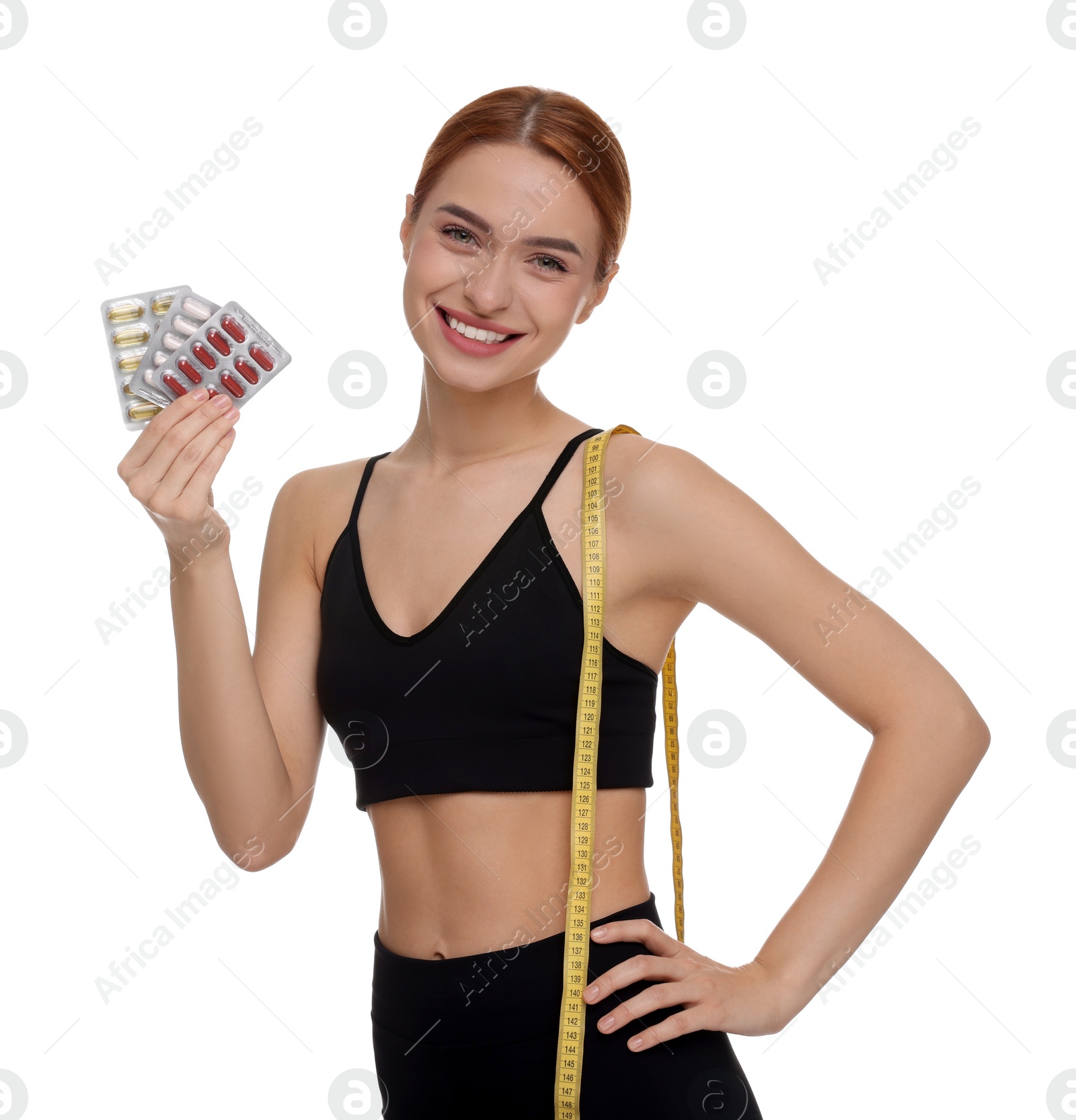 Photo of Happy young woman with pills and measuring tape on white background. Weight loss