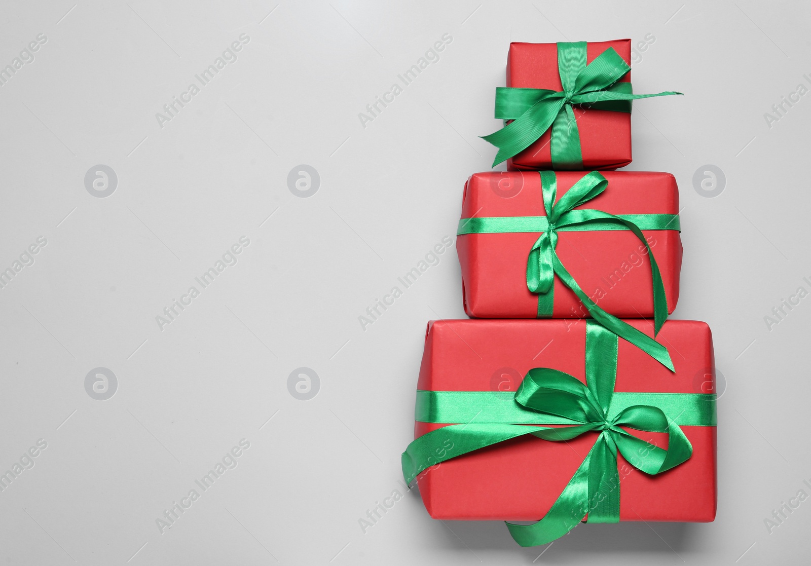 Photo of Christmas tree shape of gift boxes on light grey background, flat lay. Space for text