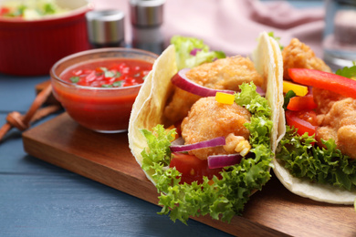 Photo of Delicious fish tacos served on blue wooden table, closeup