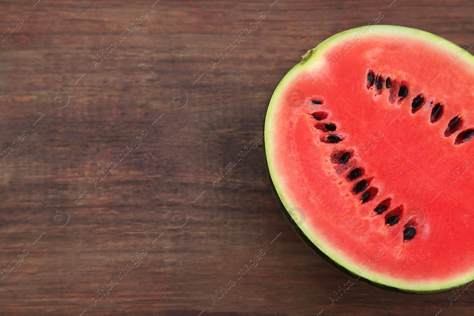 Photo of Half of delicious ripe watermelon on wooden table, top view. Space for text