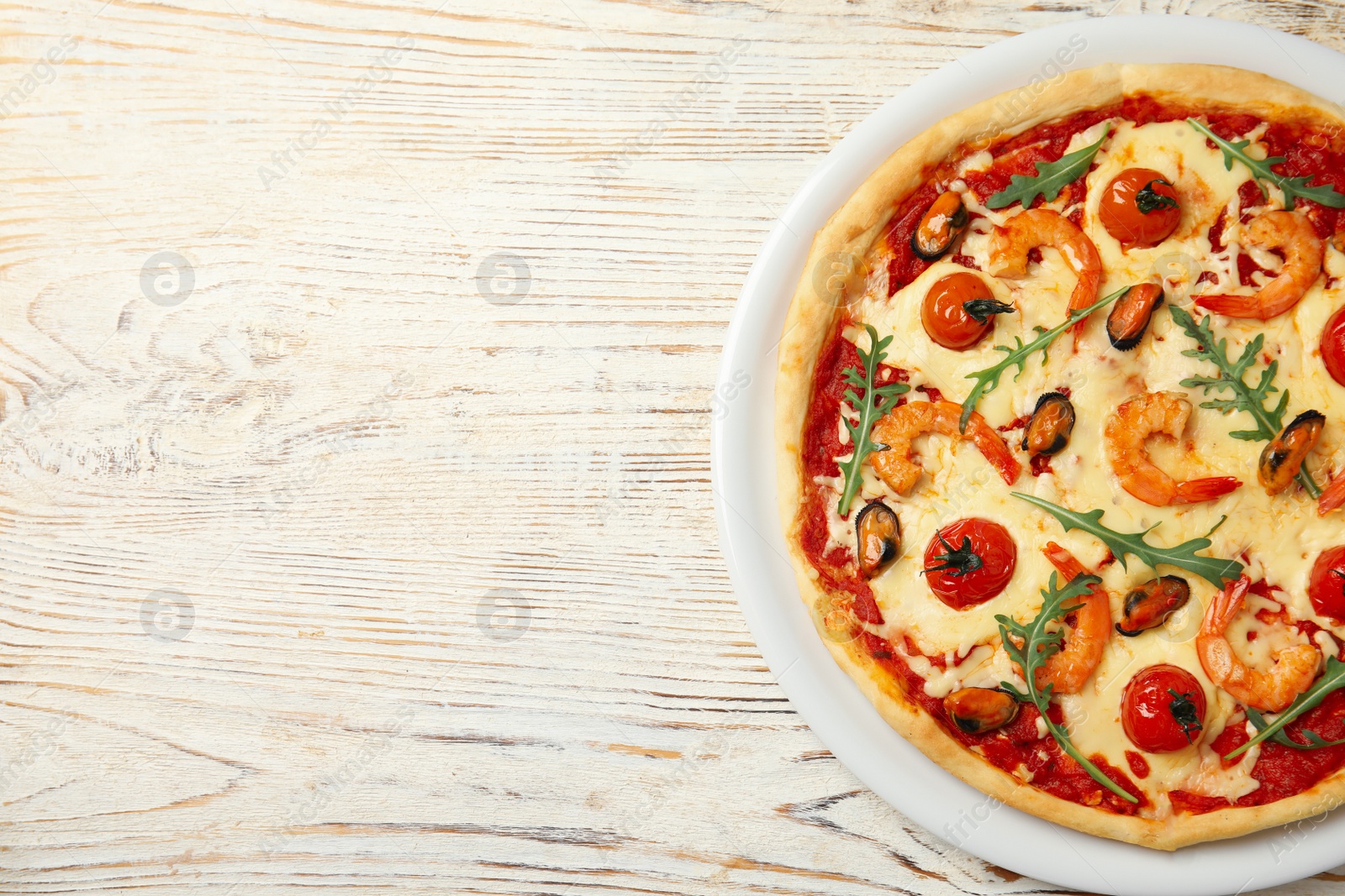 Photo of Delicious seafood pizza on white wooden table, top view. Space for text