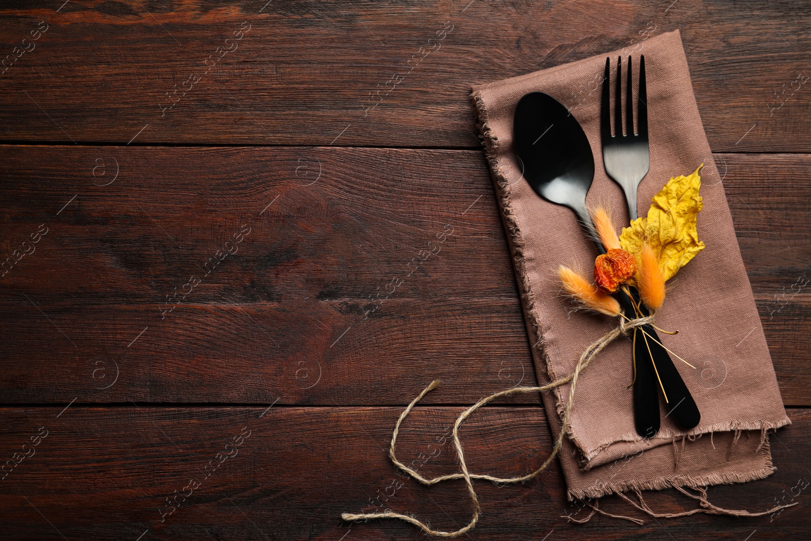 Photo of Seasonal table setting on wooden background, space for text. Cutlery with autumn decorations, top view