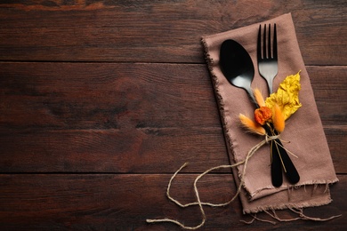 Seasonal table setting on wooden background, space for text. Cutlery with autumn decorations, top view