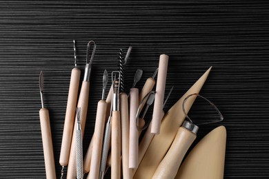 Photo of Clay and set of modeling tools on dark gray wooden table, flat lay