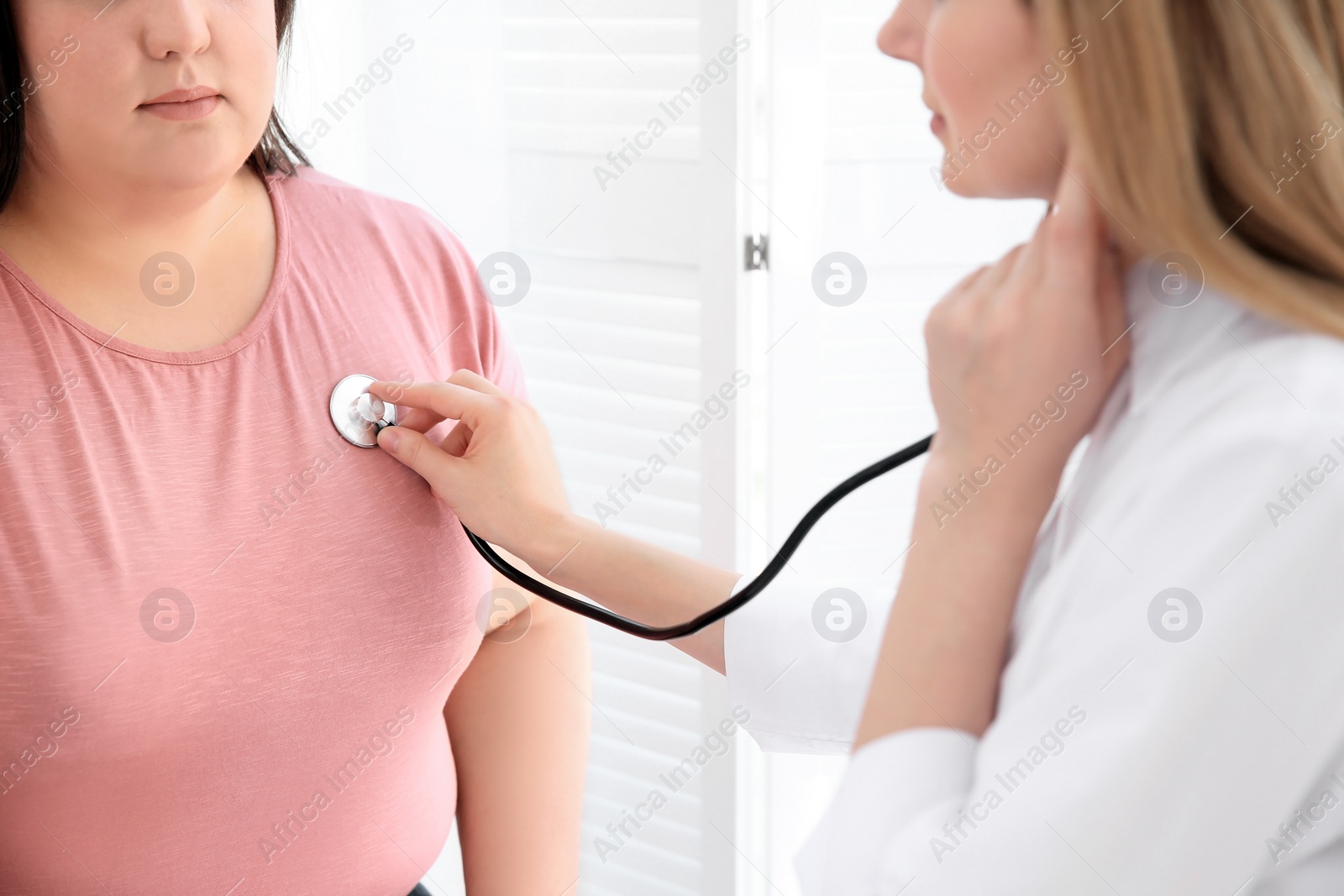 Photo of Female doctor listening to patient's heartbeat with stethoscope in clinic