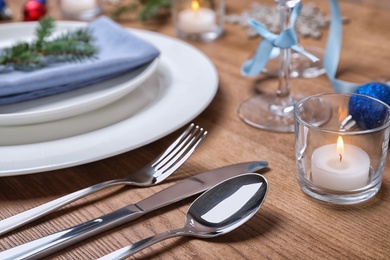 Photo of Cutlery, plates, napkin and Christmas decor on wooden table, closeup