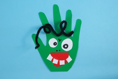 Funny green hand shaped monster on light blue background, top view. Halloween decoration