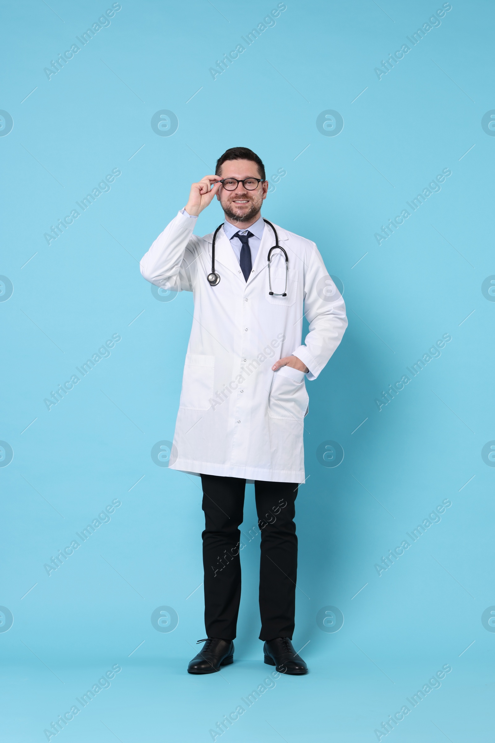 Photo of Full length portrait of smiling doctor on light blue background