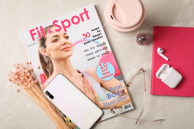 Photo of Sports magazine, smartphone and women's accessories on light table, flat lay