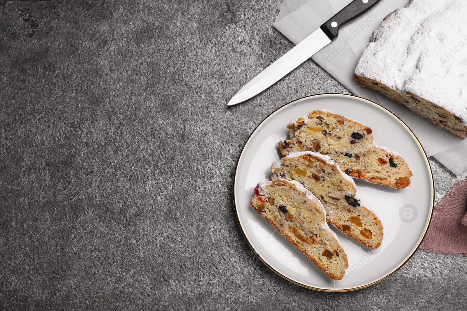 Photo of Traditional Christmas Stollen with icing sugar on grey table, flat lay. Space for text