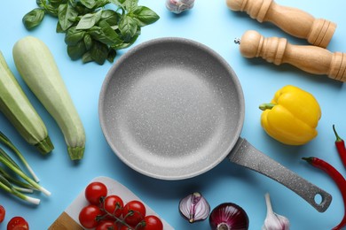 Flat lay composition with frying pan and fresh products on light blue background