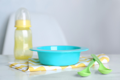 Photo of Set of plastic dishware on white table indoors. Serving baby food