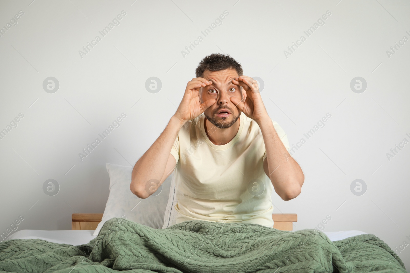 Photo of Sleepless man sitting on bed at home