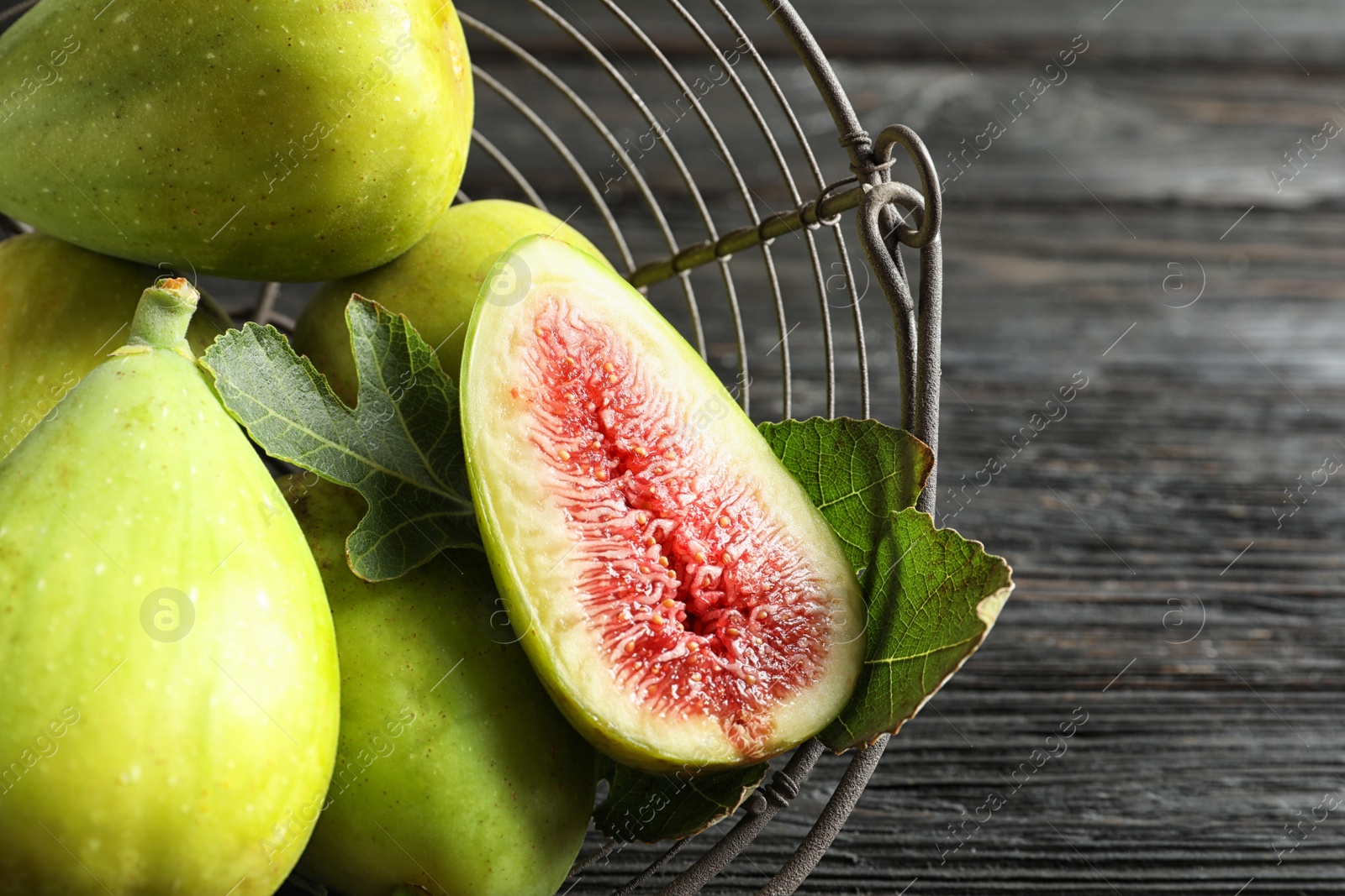 Photo of Fresh ripe figs in basket on wooden table, top view. Tropical fruit