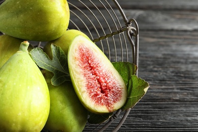 Fresh ripe figs in basket on wooden table, top view. Tropical fruit