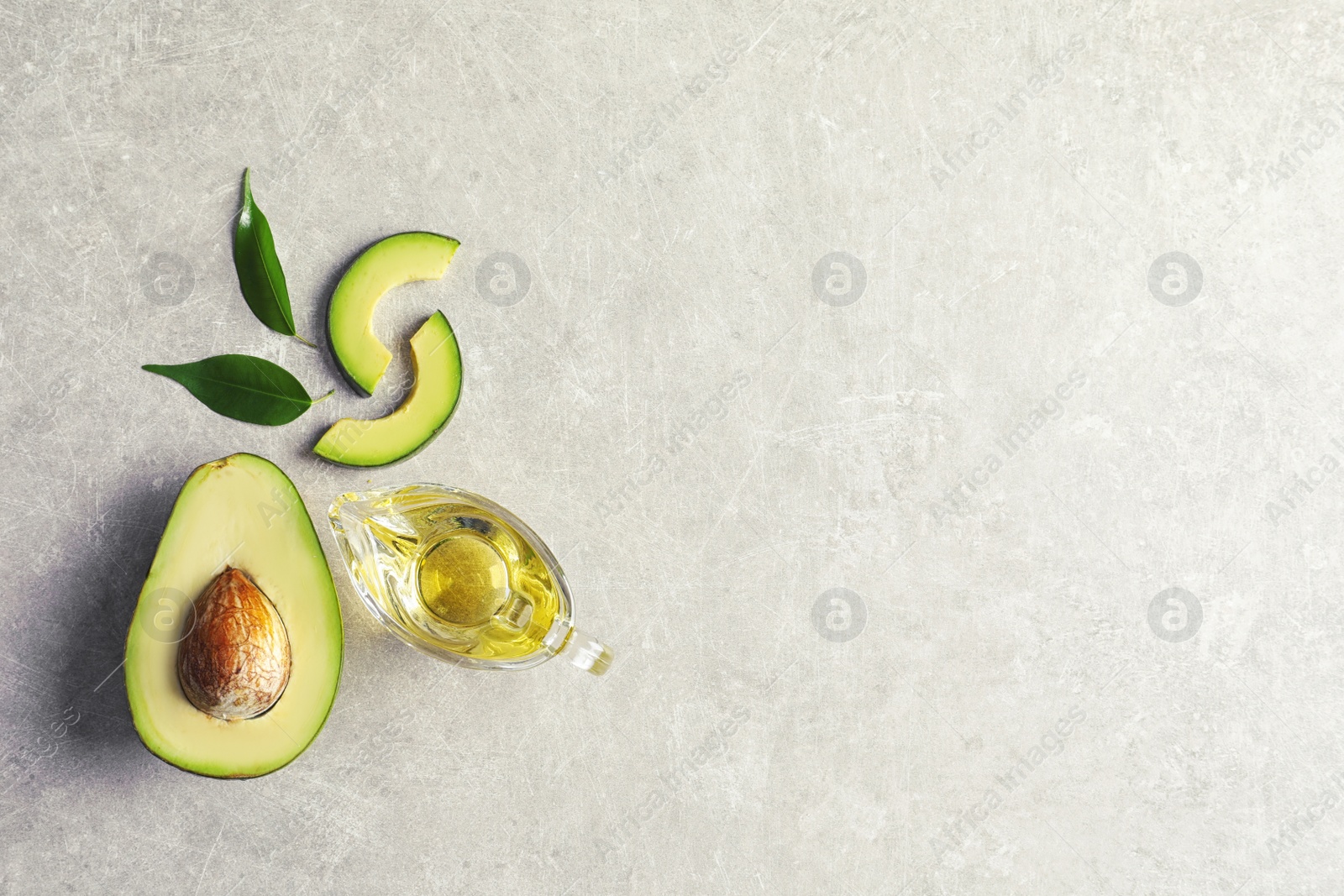 Photo of Gravy boat with oil and ripe fresh avocado on table, top view