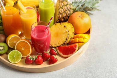 Photo of Wooden tray with glasses of different juices and fresh fruits on table