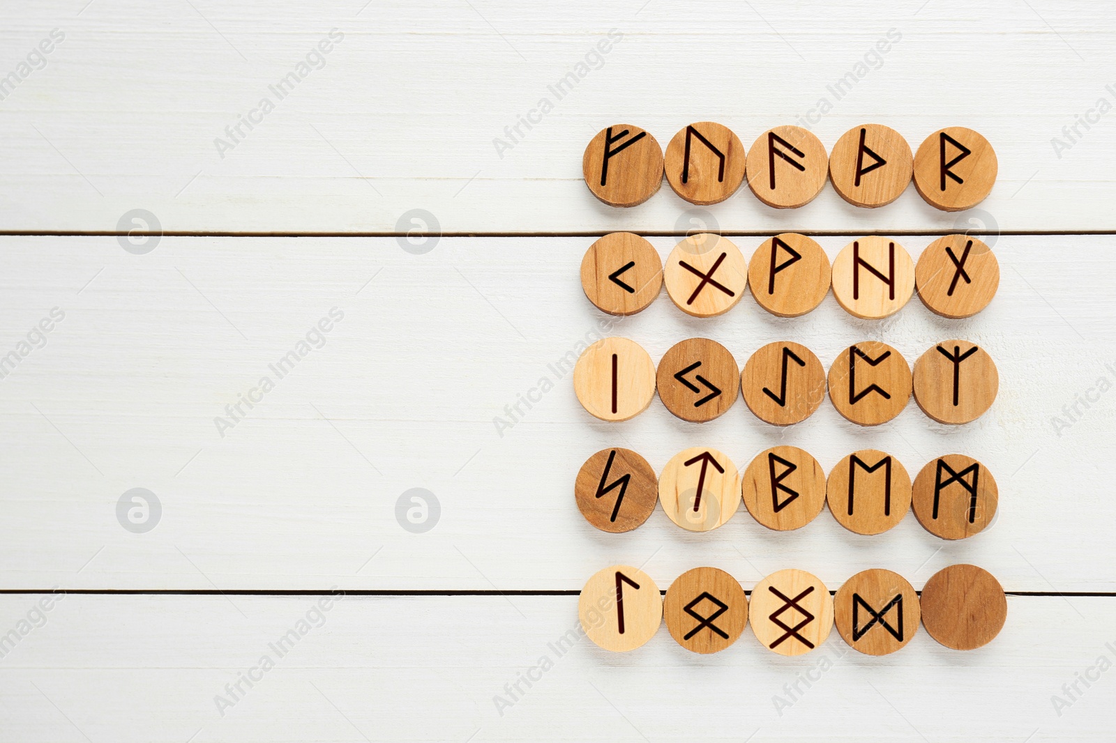 Photo of Runes with different symbols on white wooden table, flat lay. Space for text