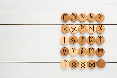 Photo of Runes with different symbols on white wooden table, flat lay. Space for text