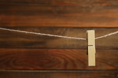 Clothespin on rope against wooden background. Space for text