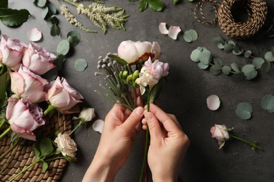 Photo of Florist creating beautiful bouquet at black table, top view