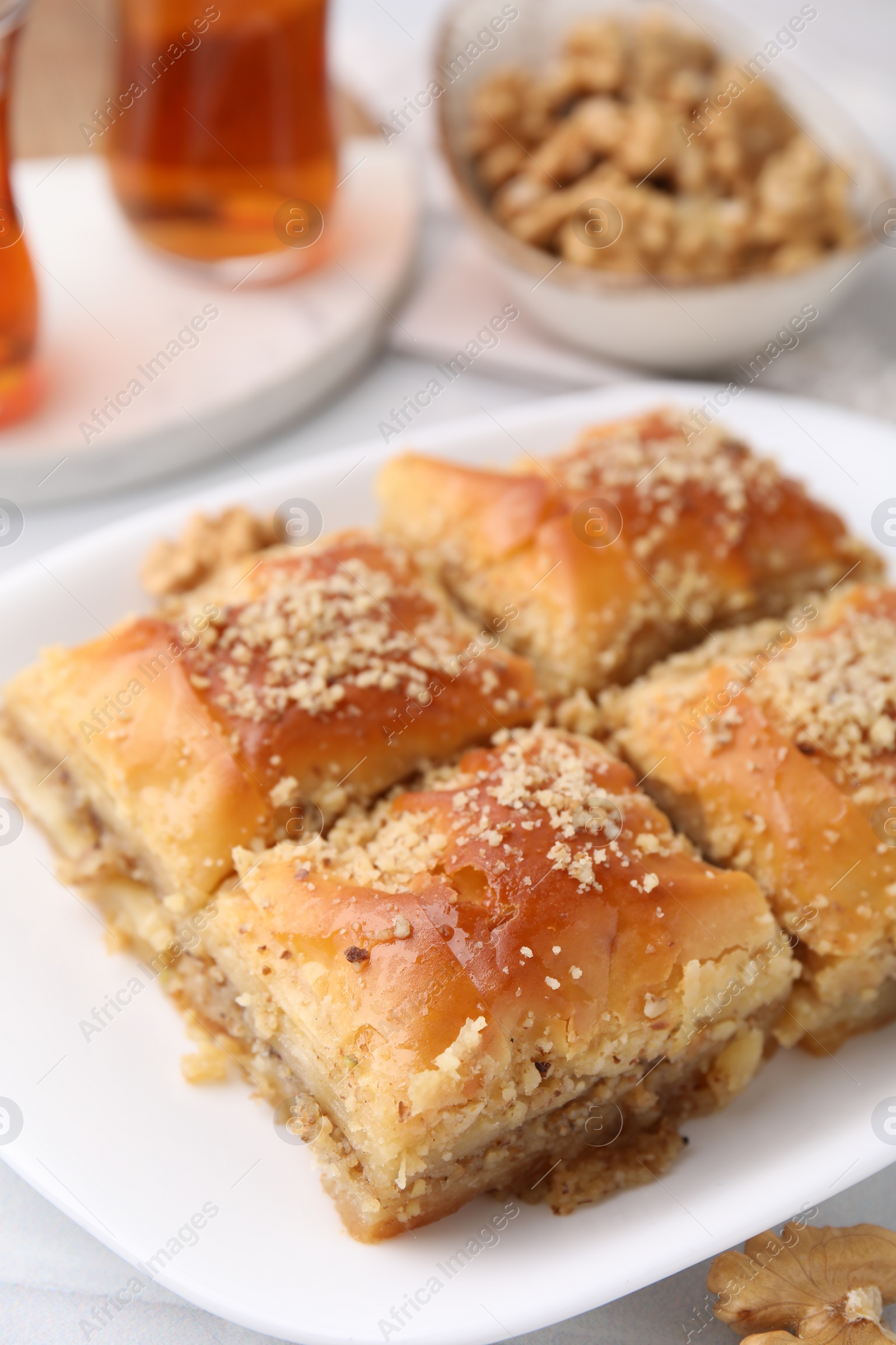 Photo of Eastern sweets. Pieces of tasty baklava and tea on white table, closeup