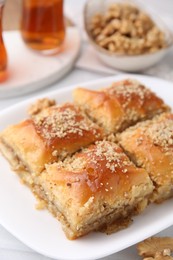 Photo of Eastern sweets. Pieces of tasty baklava and tea on white table, closeup