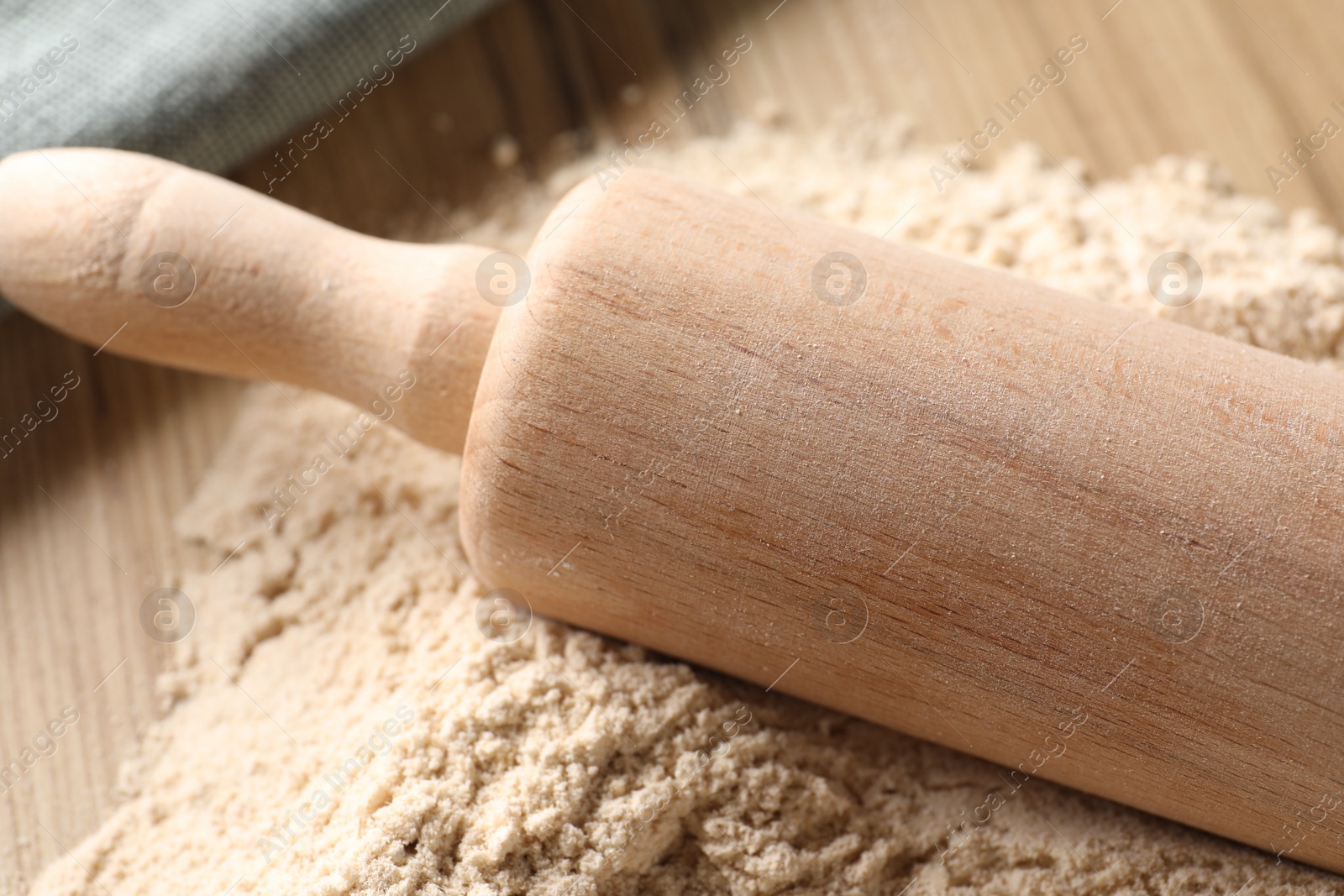 Photo of Pile of flour and rolling pin on wooden table, closeup