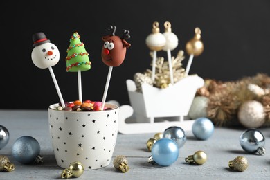 Delicious Christmas themed cake pops and festive decor on wooden table against black background