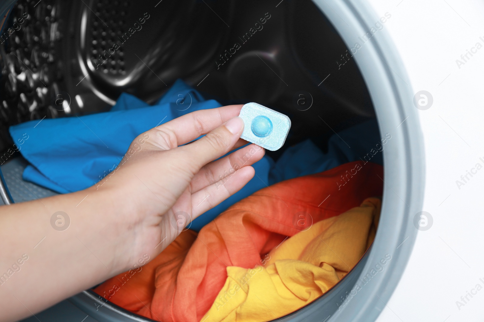 Photo of Woman putting water softener tablet into washing machine, closeup