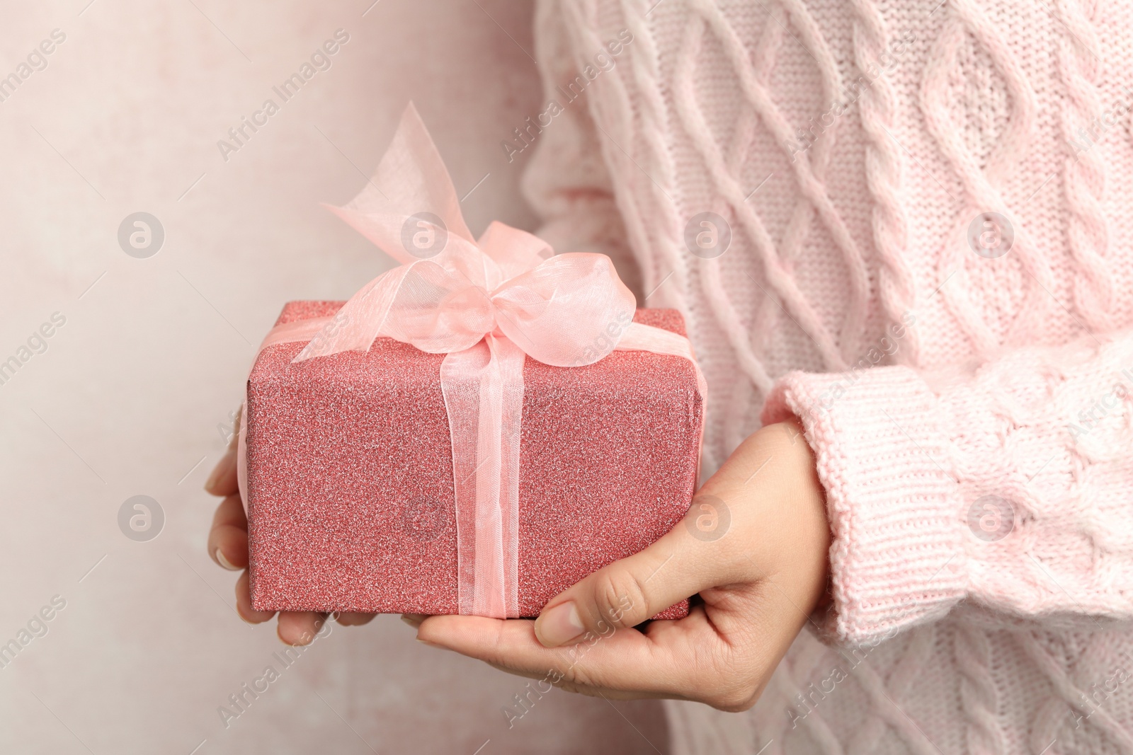 Photo of Woman holding beautiful Christmas gift on light background, closeup