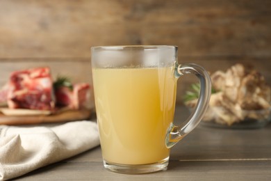 Photo of Glass cup with delicious bone broth on wooden table
