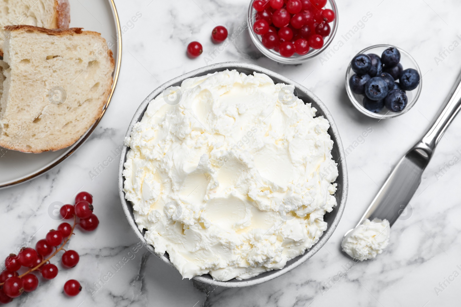 Photo of Tasty cream cheese, fresh berries and bread on white marble table, flat lay