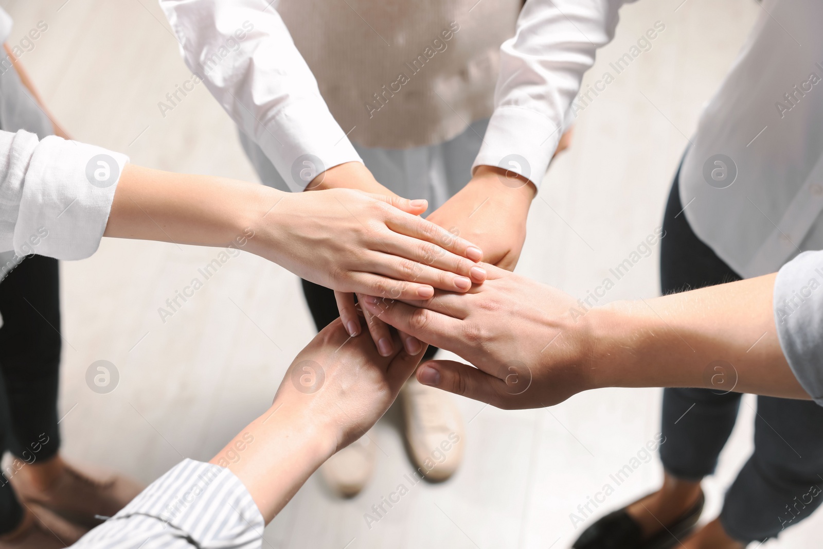 Photo of Group of people holding hands together indoors, above view. Unity concept