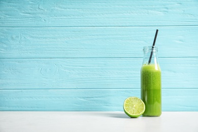 Photo of Bottle with delicious detox juice and lime on table