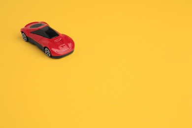 Photo of One red car on yellow background, space for text. Children`s toy