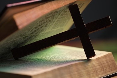 Photo of Cross and Bible in color lights, closeup. Religion of Christianity